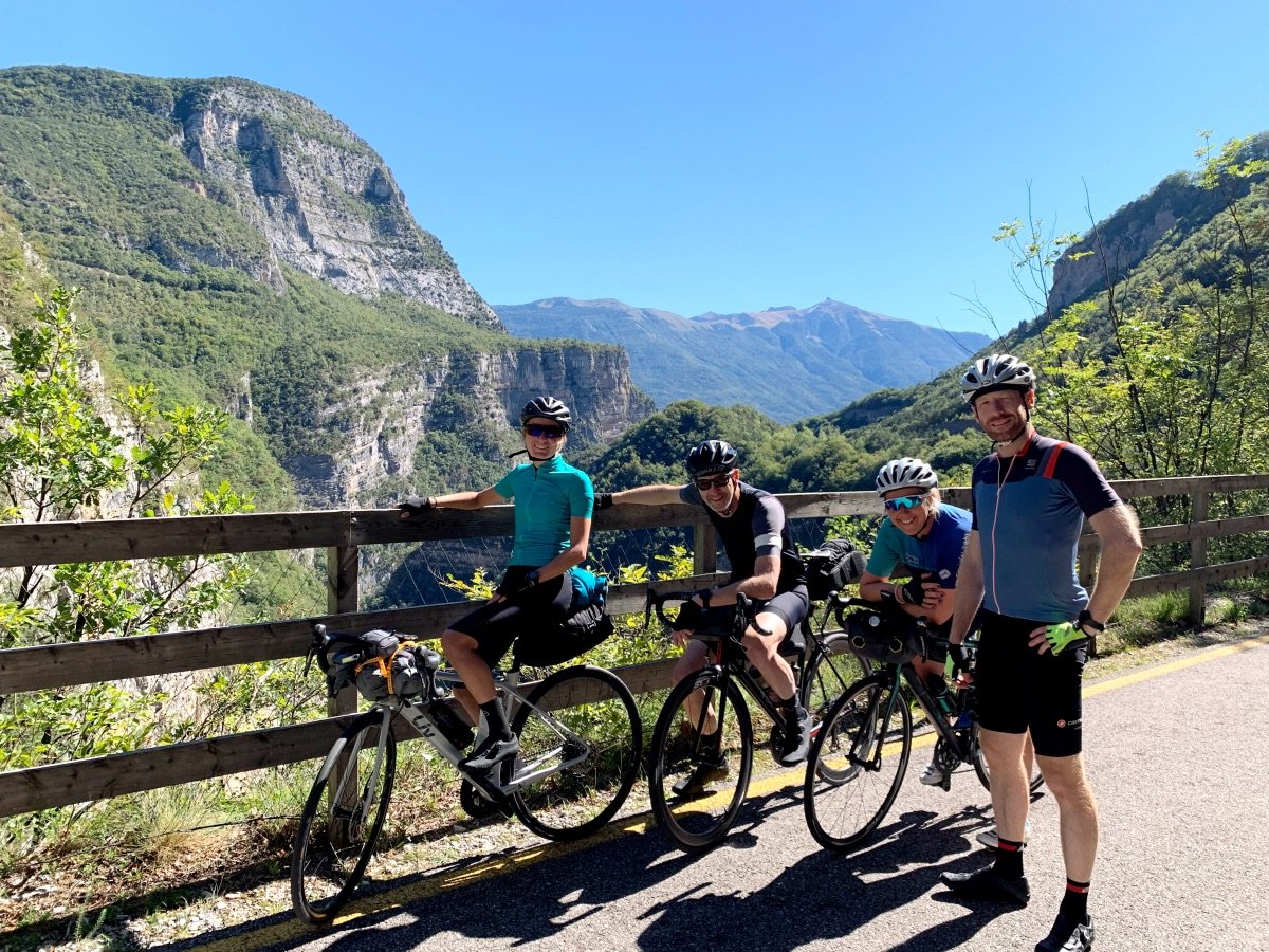 Groep wielrenners van Rudi Rides op fietspad langs vallei in Italiaanse Alpen nabij Sarche 
