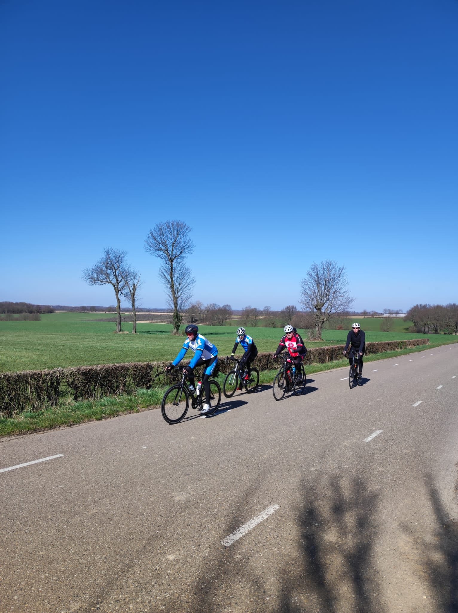 Groep fietsers in limburg in het voorjaar naast een weiland