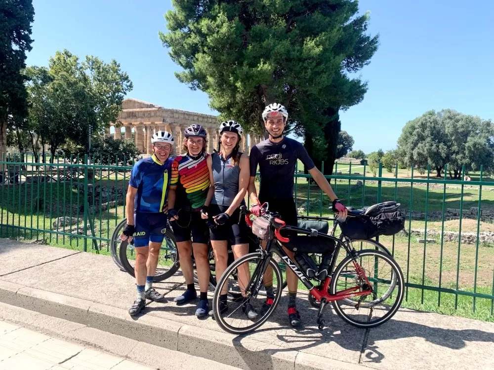 Groep fietsers voor Griekse tempel in Paestum