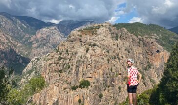 Wielrenner in bolletjestrui met op achtergrond rotsachtig gebergte in de buurt van Porto op Corsica