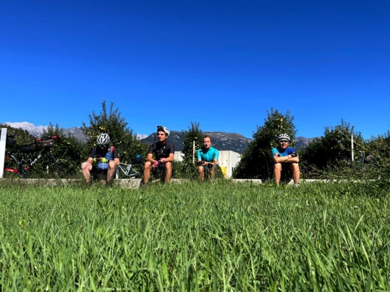 Foto in laag perspectief boven het gras zitten fietsers in de zon een appel te eten voor een appelgaard