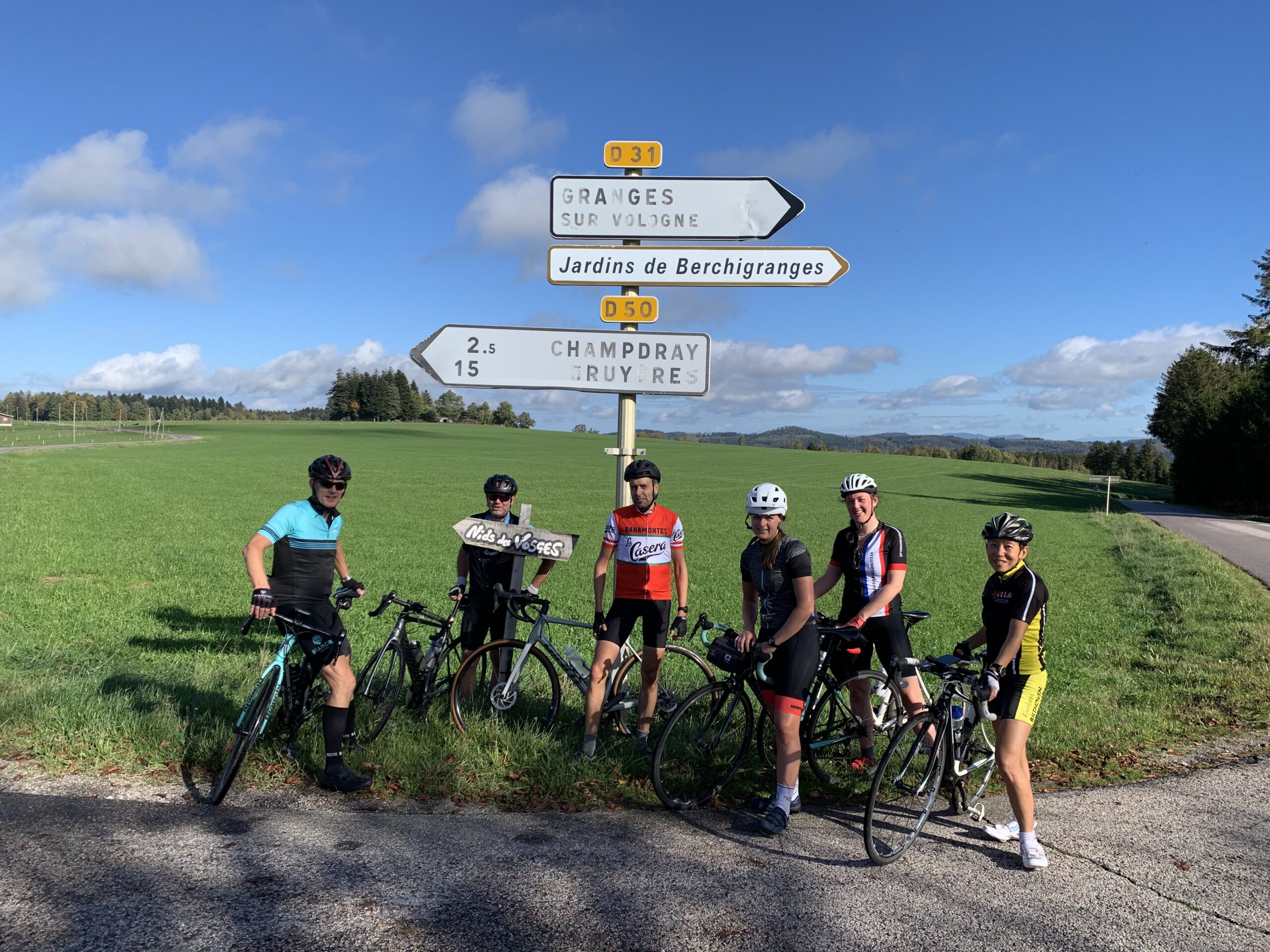 Groep fietsers van Rudi Rides in de zon voor verkeersbord in Frankrijk in de Vogezen