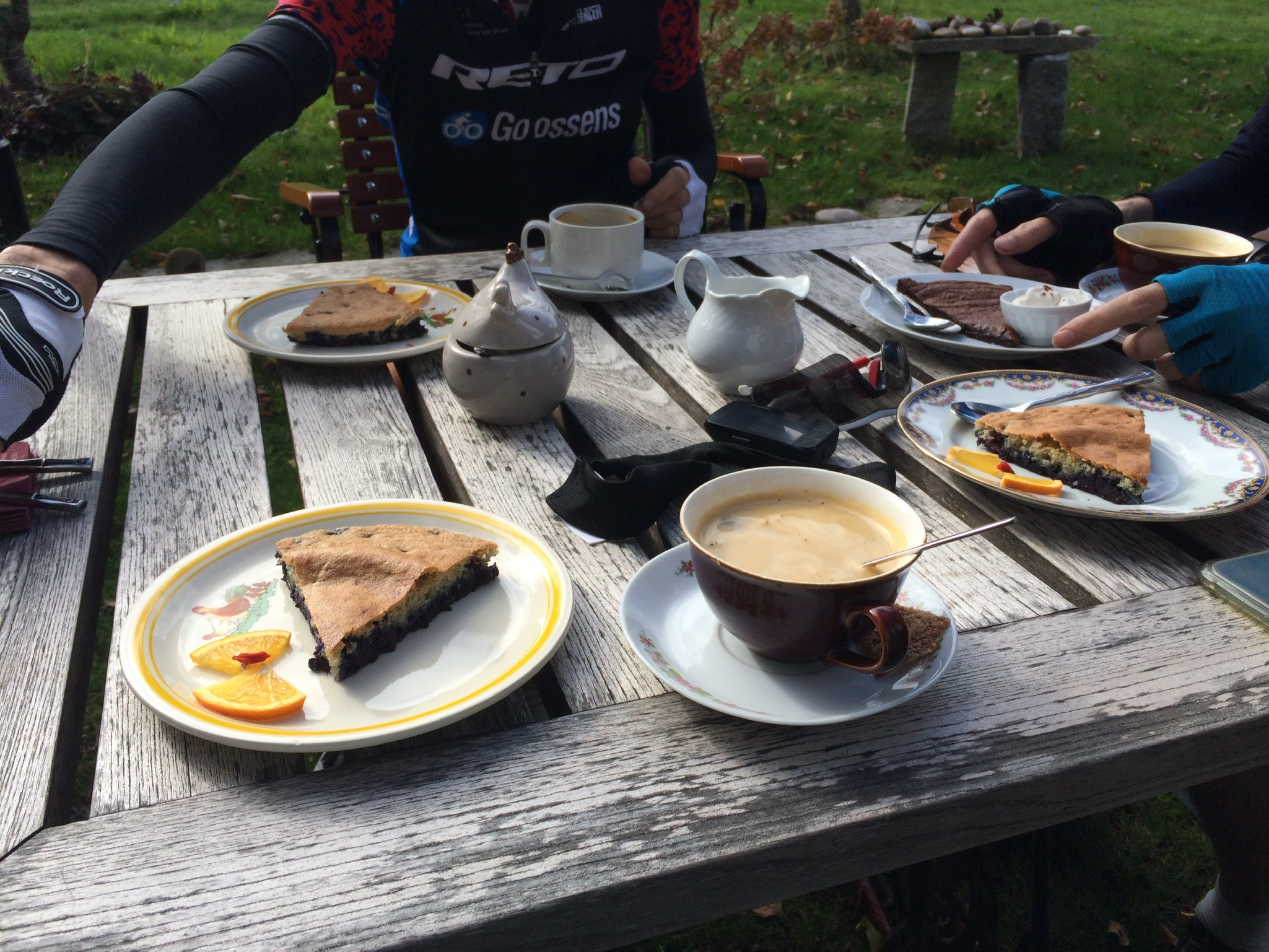 Koffie en gebak op houten tafel in tuin met fietsattributen