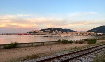 Treinrails met op achtergrond havenstad Ajaccio in de ochtendzon