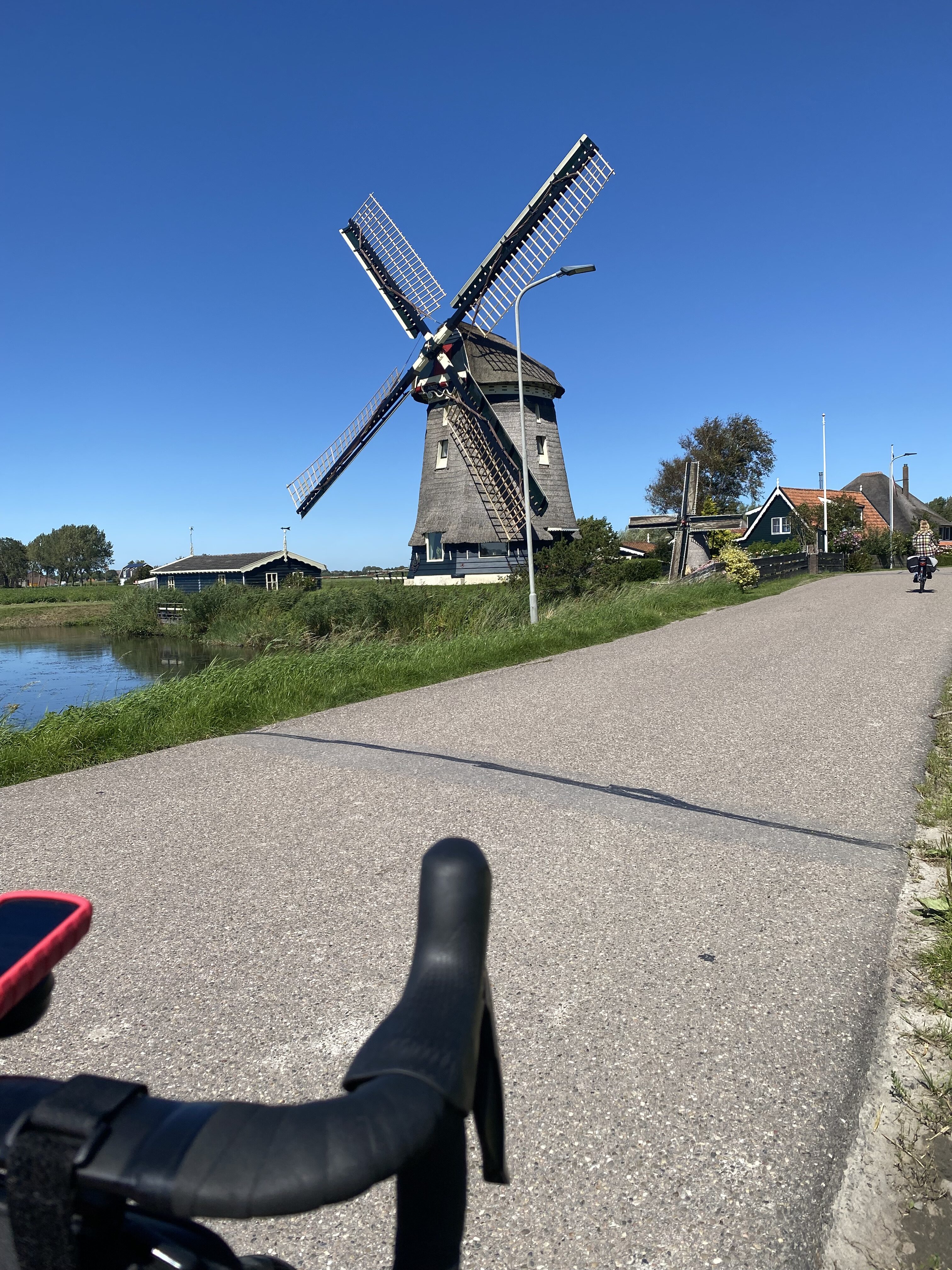 Windmolen in Nederlands landschap met racefiets stuur op voorgrond