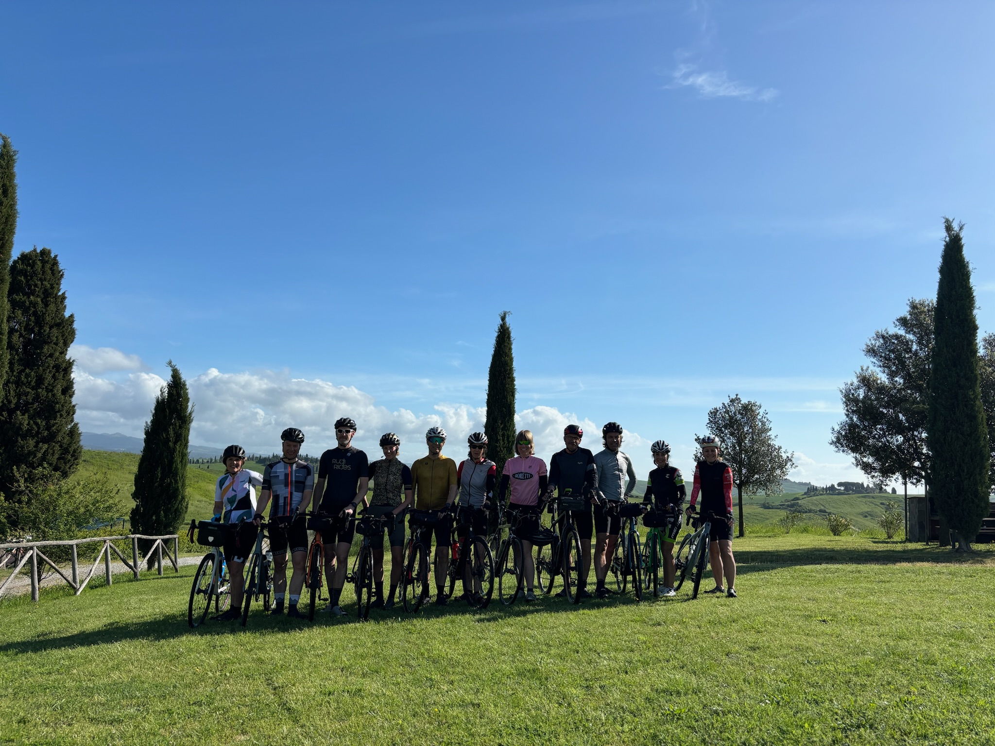 Groep fietsers van Rudi Rides bij een agriturismo met rondom typische cipressen