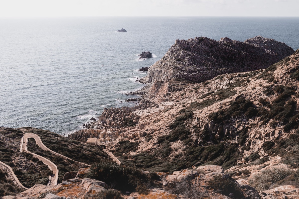 Kliffen op eiland San Pietro bij Sardinië met slingerweg richting de zee.