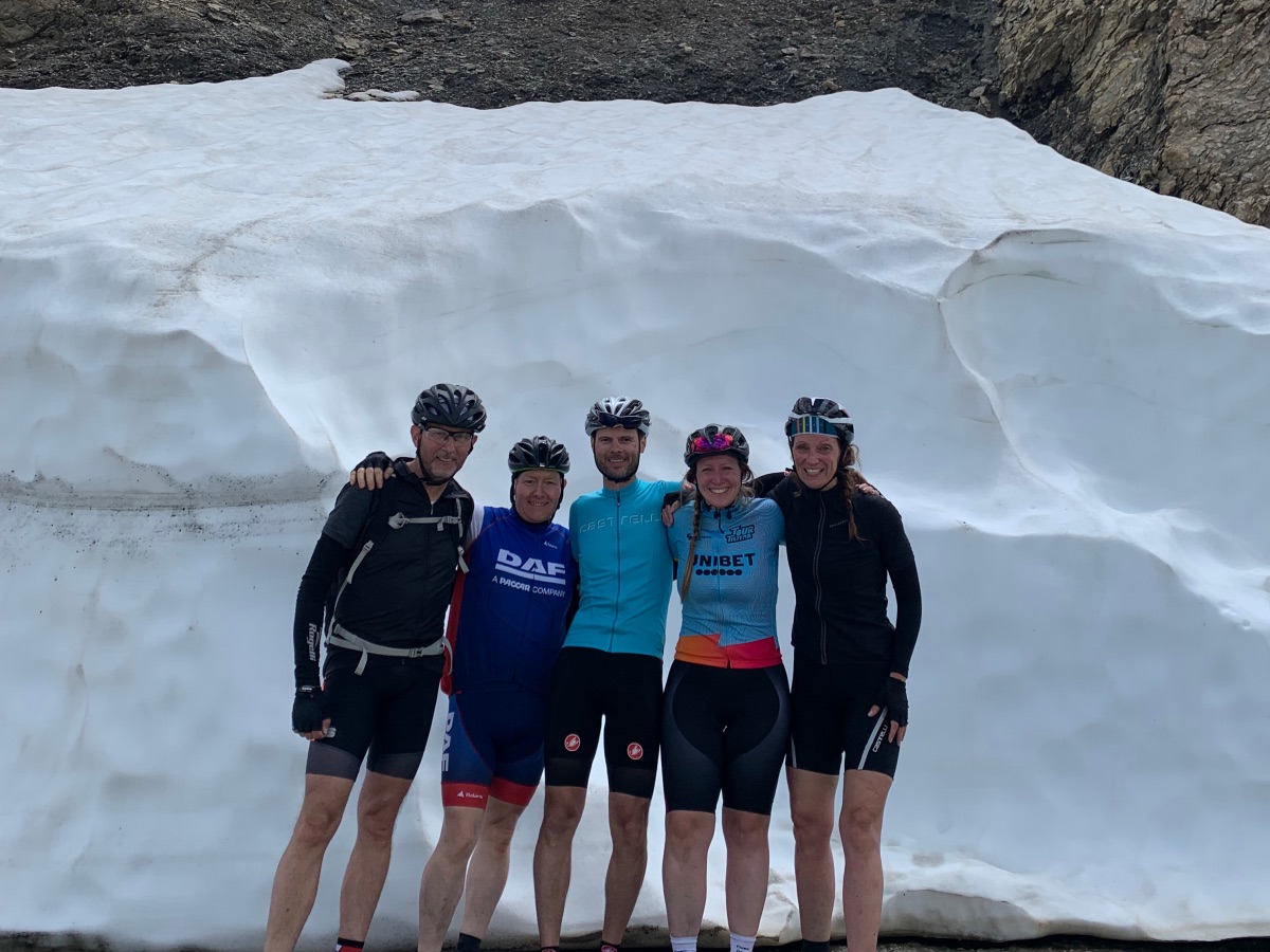 Groep wielrenners op Col du Galibier met op achtergrond veel sneeuw. In juni.
