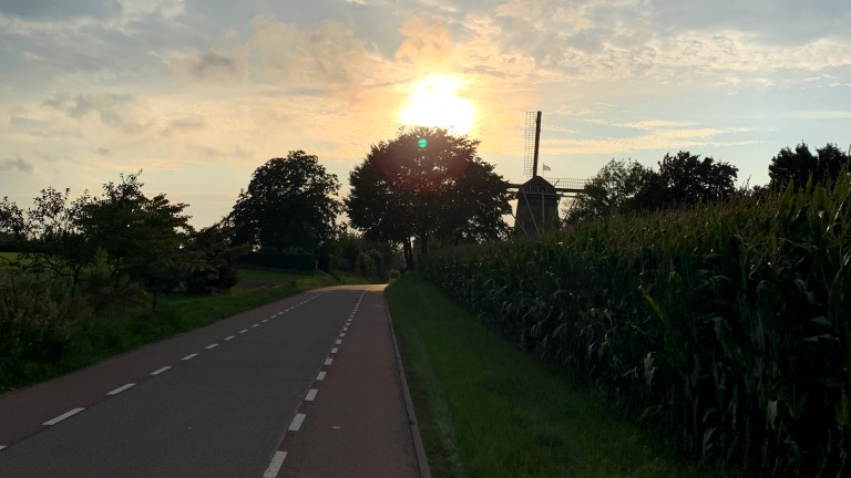 Nederlandse weg met goed asfalt en molen op de achtergrond