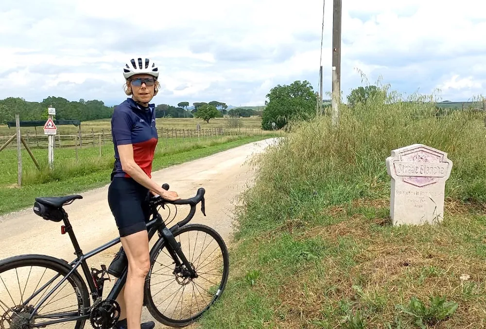 Fietser bij bordje van Strade Bianche Vrouwelijke fietser bij een bordje van Strade Bianche in Toscane Italië