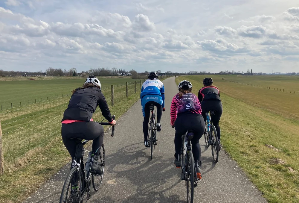 Nederland_Posbank_Dijk_horizontaal_achterkant Wielrenners op de dijk vanaf de achterkant in het voorjaar in Nederland