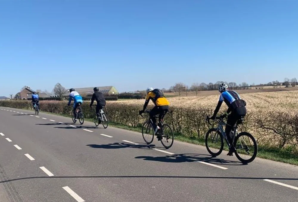 Nederland_Limburg_voorjaar_groep_achterkant Fietsers in Limburg naast een gemaaid veld in het voorjaar in de zon