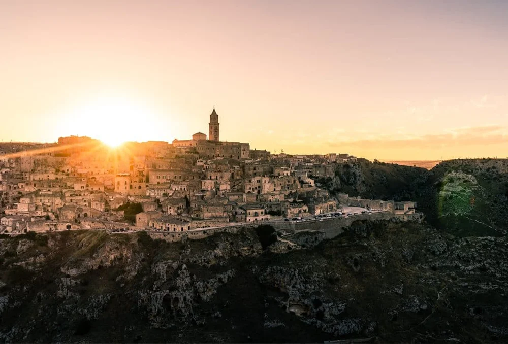 Italie_Zuid_matera_stad_zonsondergang_vanaf_belvedere_overkant Witte huizen gebouwd op heuvel in Zuid Italië tijdens zonsondergang: Matera.