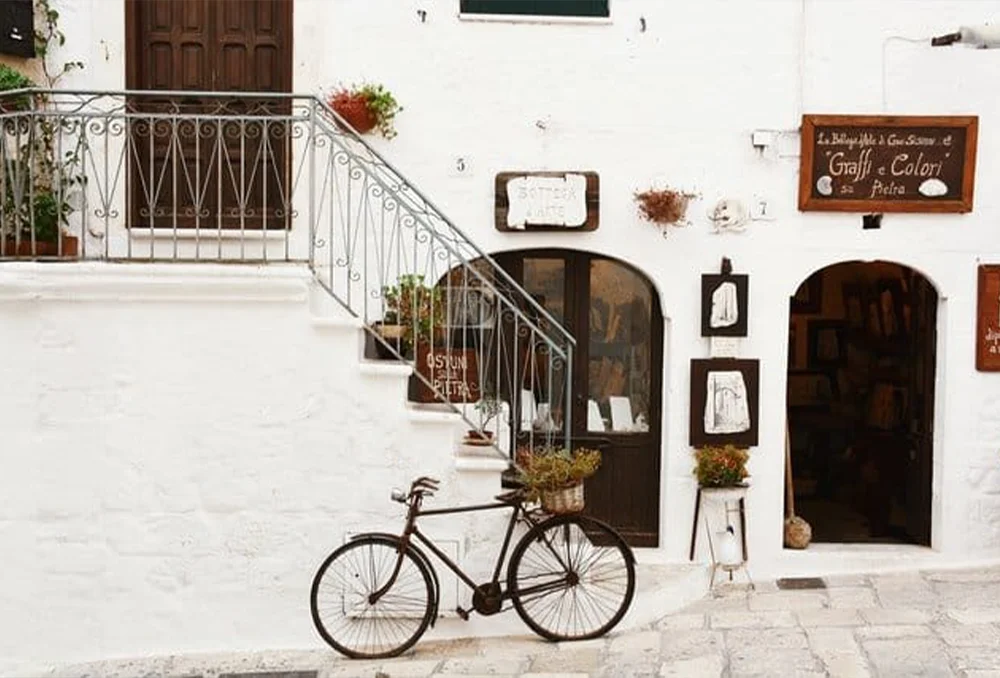 Italie_Zuid_ostuni_kust_italie_met_fiets Oude fiets tegen witte muur in Zuid Italiaanse stad Ostuni
