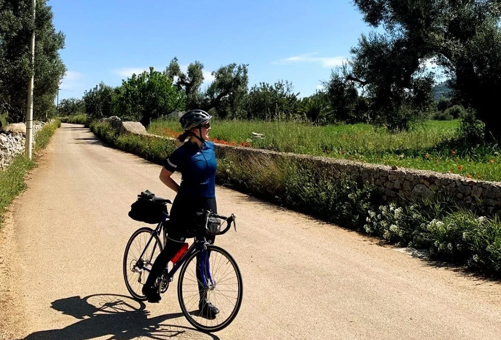 Olijfbomen op een verlaten weg in Puglia Zuid-Italië Fietser tussen de olijfbomen op de weg ergens in een afgelegen gebied van Puglia in Zuid-Italië