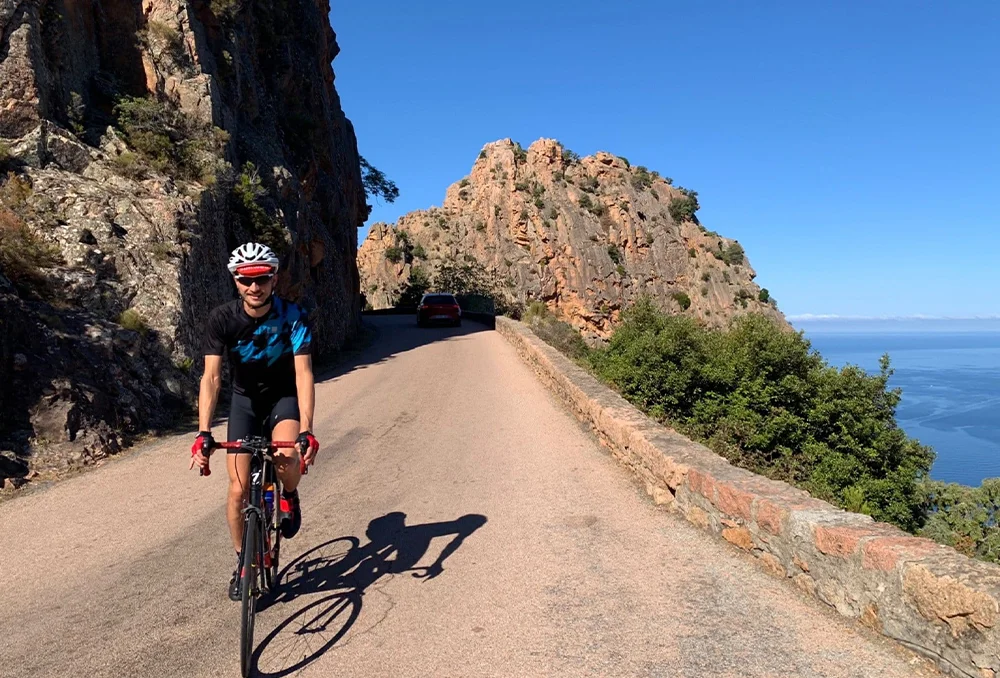 Rudi Rides bij Calanches de Piana op Corsica Een fietser van Rudi Rides fietst langs Calanches de Piana op Corsica